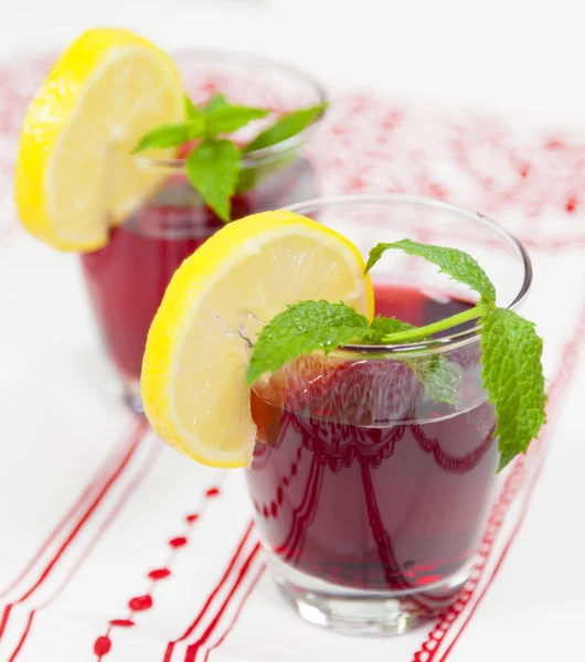 Two glasses of red fruit juice with lemon