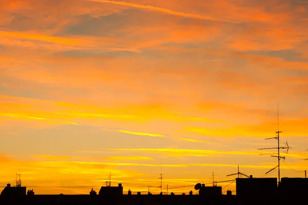 Urban sunset rooftops antenas and clouds