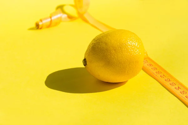 Lemon on yellow background and measure tape, concept lose weight