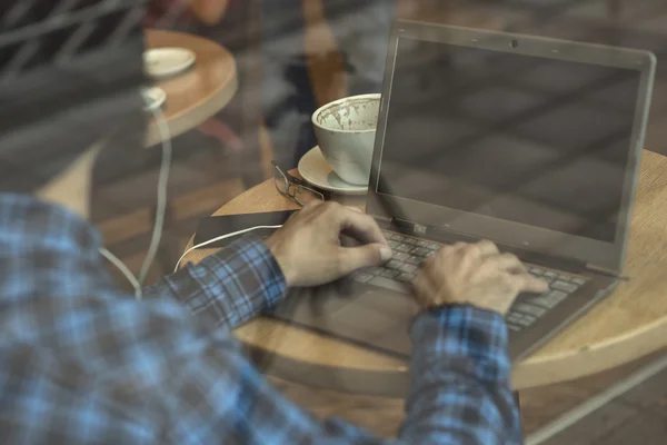 Young hipster man working on laptop in coffee shop