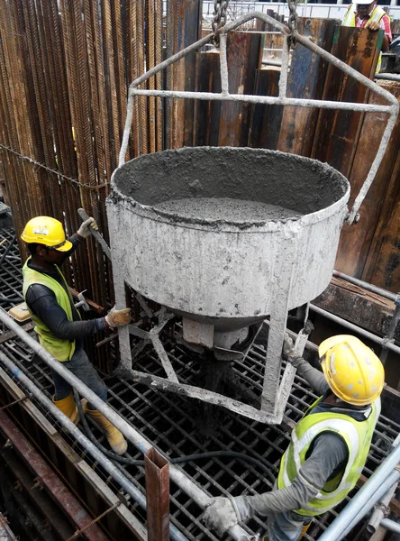 A group of construction workers pouring concrete into pile cap form work