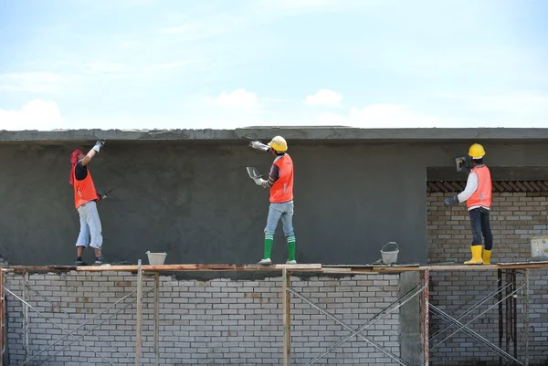 Group of construction workers plastering wall
