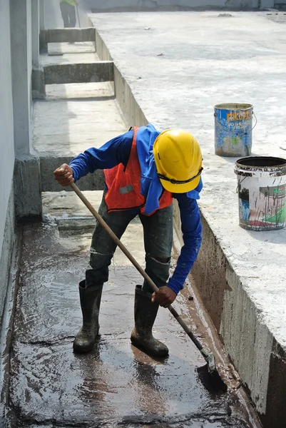 A construction worker apply layer of waterproofing at the building roof slab surface