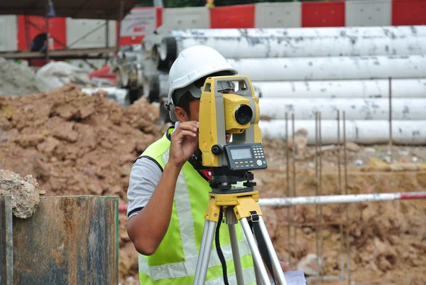 Surveyor using survey equipment at the construction site