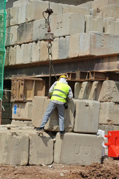 Construction workers hoisting load test block at the construction site