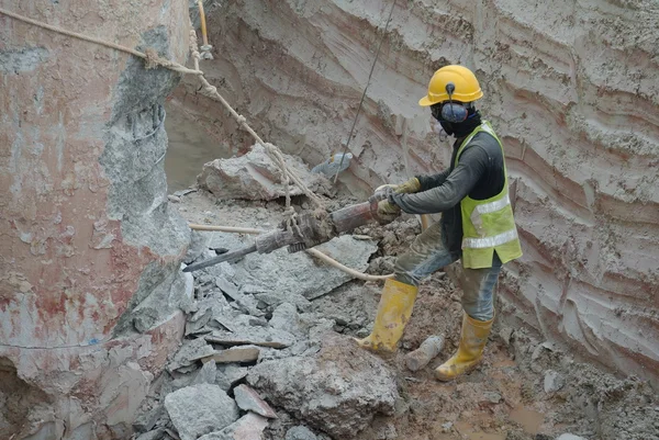 Construction workers using mobile concrete hacker at the construction site