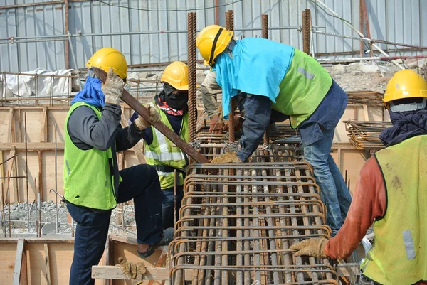 Construction workers fabricating ground beam reinforcement bar