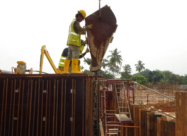 Construction workers pouring concrete slurry into reinforcement concrete wall formwork