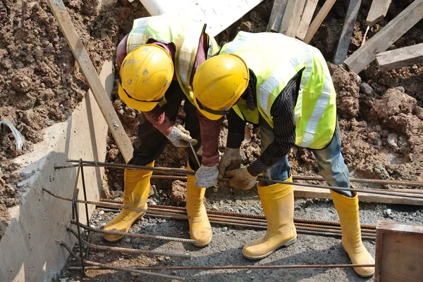 Group of construction workers fabricating ground beam steel reinforcement bar