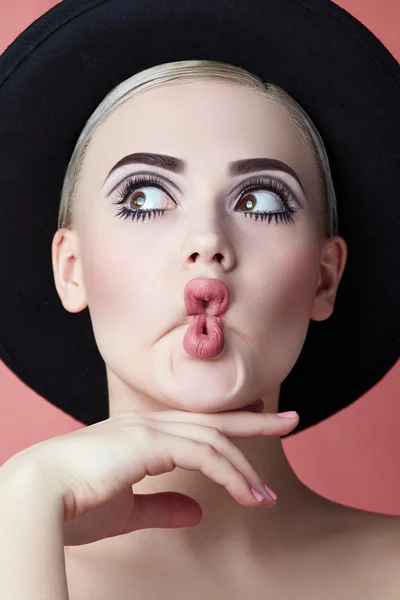 Girl in a black hat with graphic quality makeup.