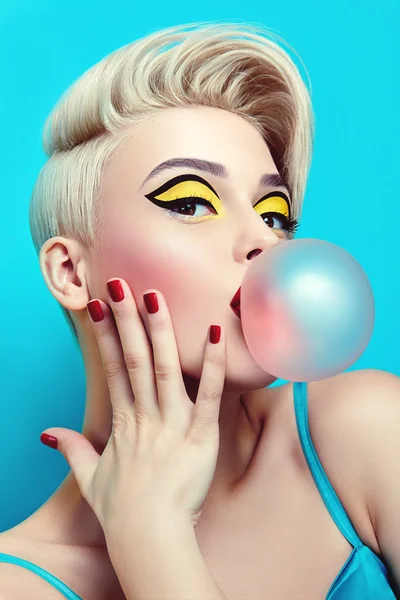 Fashionable girl with a stylish haircut inflates a chewing gum.