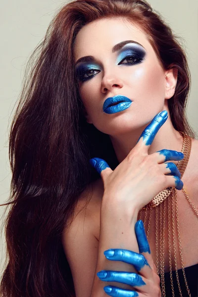 The girl\'s face with blue makeup. Hands painted in blue paint.