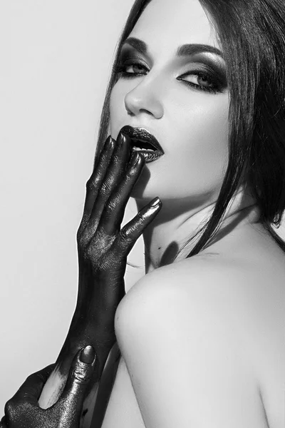 A girl with black makeup. The black paint on the hands.