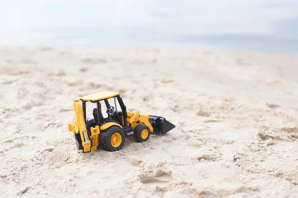 Toy excavator on the beach