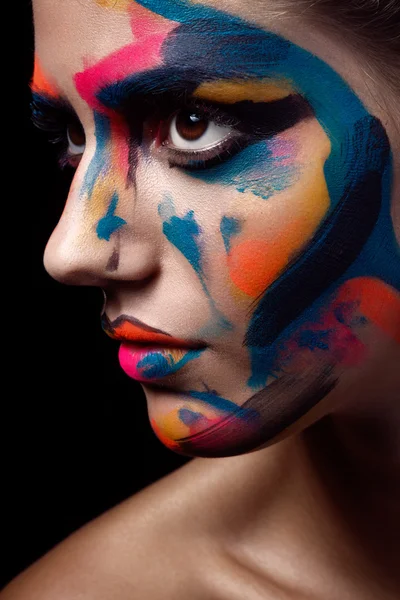 Close up portrait of a young woman with unusual makeup on a dark black background