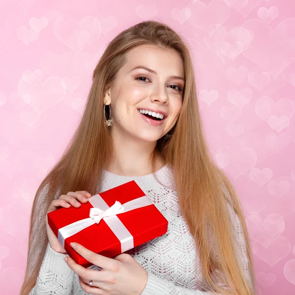 Valentines Day. Sweet blonde woman holding a gift box. heartshaped bokeh background Joyful