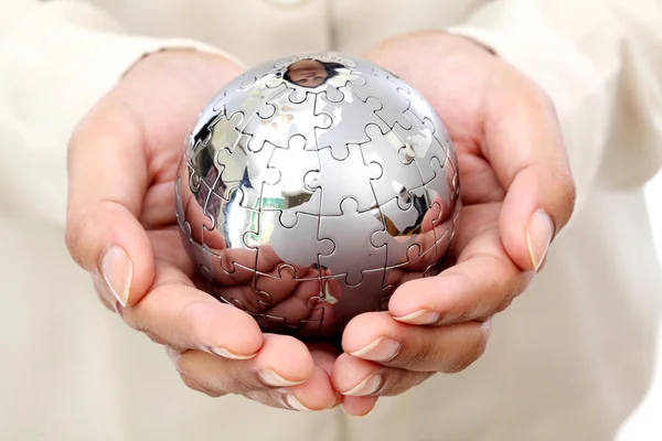 Business woman hand holding jigsaw puzzle globe