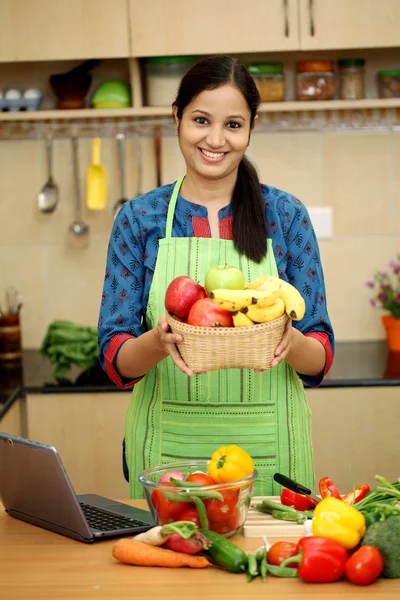 Indian woman in kitchen,holding fruit basket