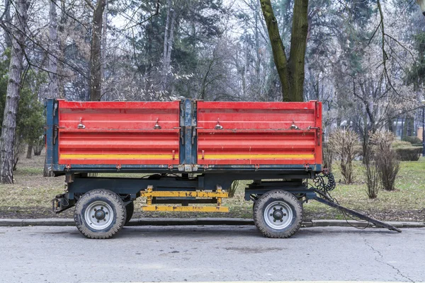 Red municipality trailer ready for park maintenance on alley