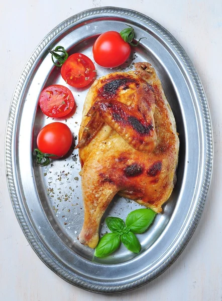 Grilled chicken with cherry tomatoes and basil on an iron plate