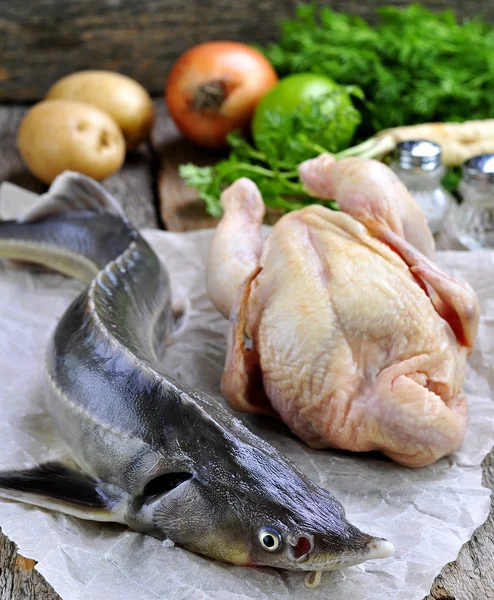 Fresh sturgeon with chicken, vegetables and spices for cooking fish soup on a wooden background. Russian traditions.