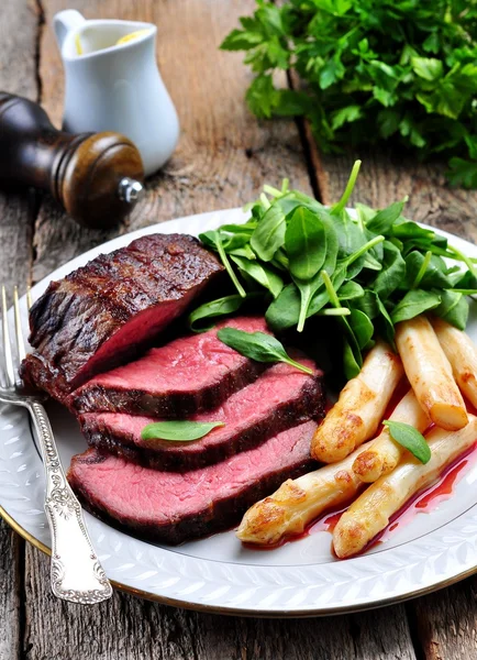 Medium rare steak with asparagus and baby spinach.