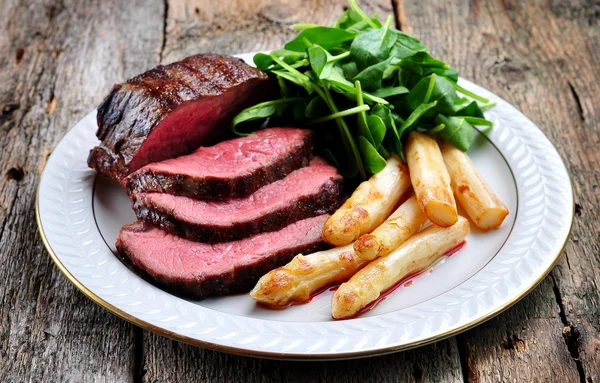 Medium rare steak with asparagus and baby spinach.