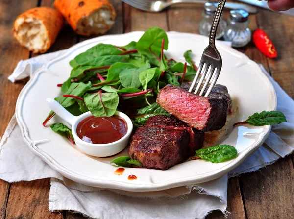 Medium steak with salad and barbecue sauce