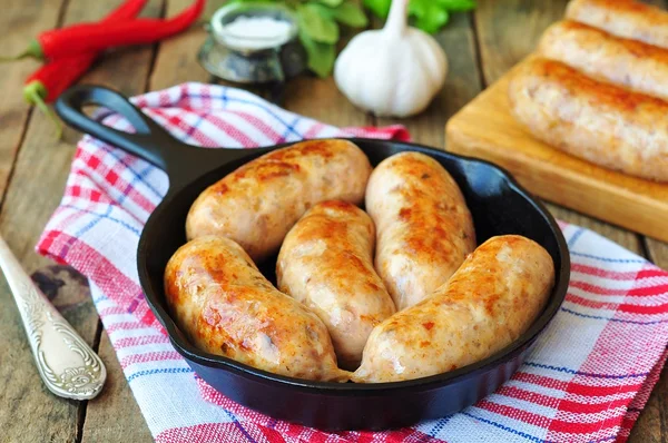 Fried chicken sausages with vegetables on a frying pan