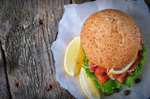 Burger with pickled salmon, lettuce, white onion and capers