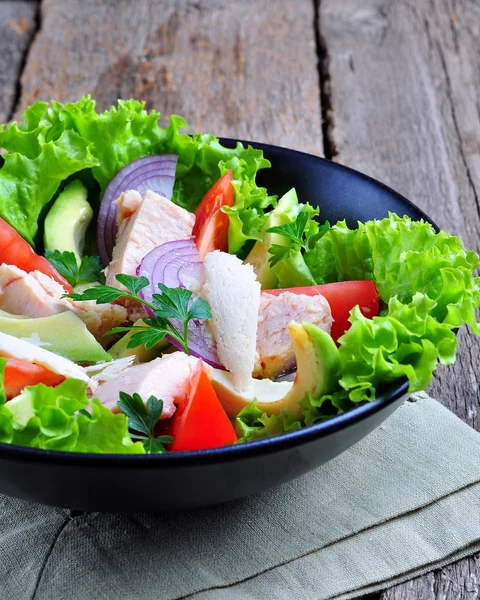 Healthy salad of avocado, tomatoes, canned tuna, onions and lettuce with parmesan, parsley and olive oil