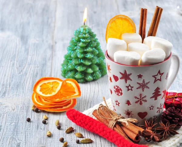 Chocolate or cocoa drink with marshmallows and cinnamon in a Christmas cup with cinnamon on gray wooden background