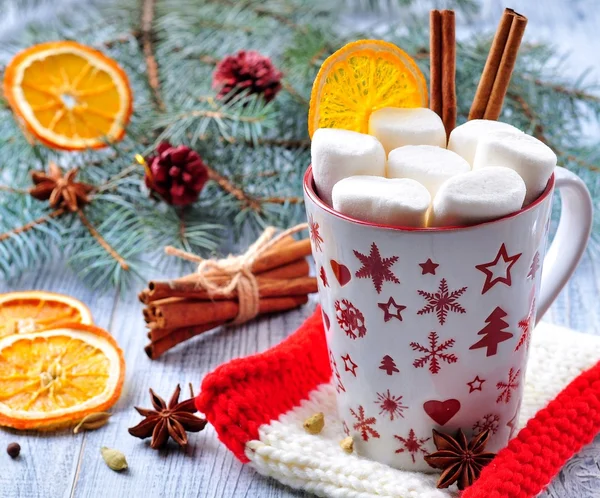 Chocolate or cocoa drink with marshmallows and cinnamon in a Christmas cup on the background of blue spruce