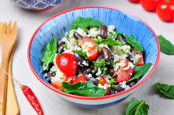 Couscous salad and brown beans, with olive oil, with organic cherry tomatoes, onion, parsley and spinach