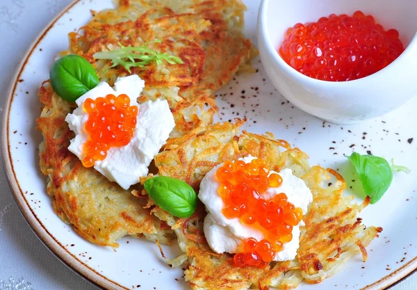 Potato pancakes with sour cream and red caviar