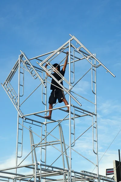Worker climbing stage equipment tower on a concert stage