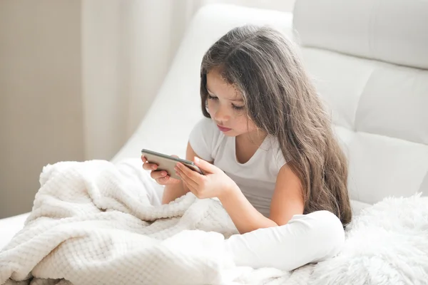 Kid girl playing games on tablet at home