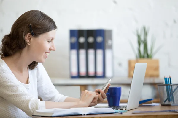 Young office woman looking at smartphone screen