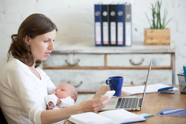 Young mom working and holding child in the office