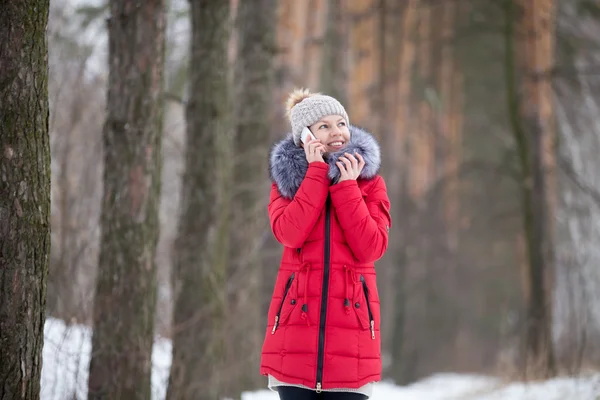 Happy smiling female in red winter jacket talks on mobile phone,