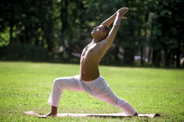 Warrior 1 yoga pose in park