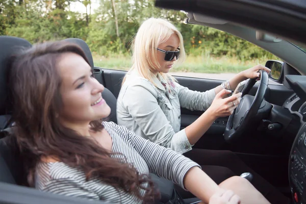 Young woman looking at mobile phone and riding car