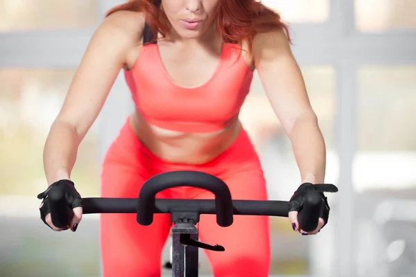 Close-up, woman training on cycling machine in fitness center