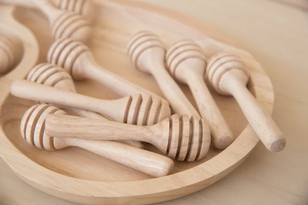 Wooden honey stick in wooden tray