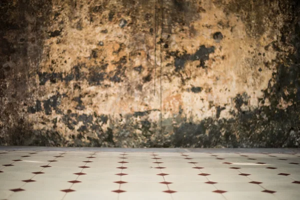 Focus on floor tiles with old weathered wall texture background
