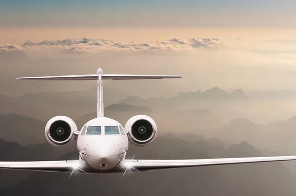 Airplane fly over clouds and Alps mountain on sunset. Front view of a big passenger or cargo aircraft, business jet, airline. Transportation, travel concept