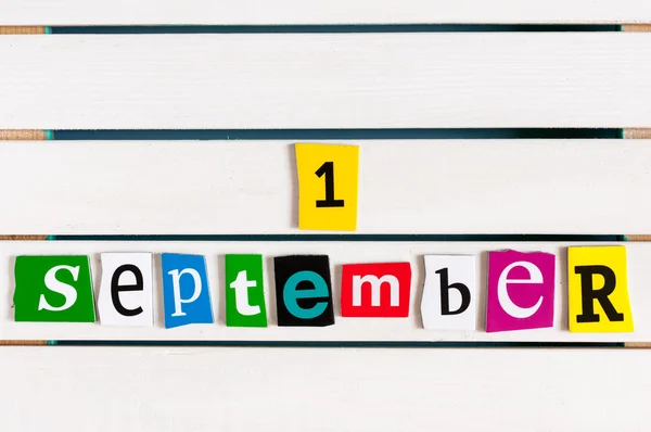 September 1st. Calendar of first or 1 day of septeber - written with color magazine letter clippings on wooden board. Back to school time.