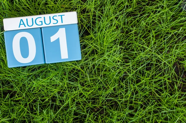 August 1st. Image of august 1 wooden color calendar on green grass lawn background. Summer day. Empty space for text