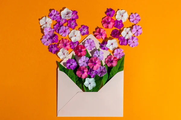 Letter love. Romantic envelope with flowers on orange background. Declaration of hot feelings. Top view. Empty space for text