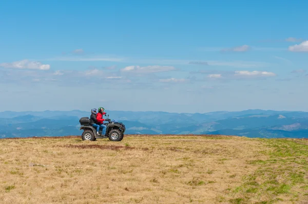 Quad biking in the mountains. Equipped ATV driver and passenger. Landscape, spring